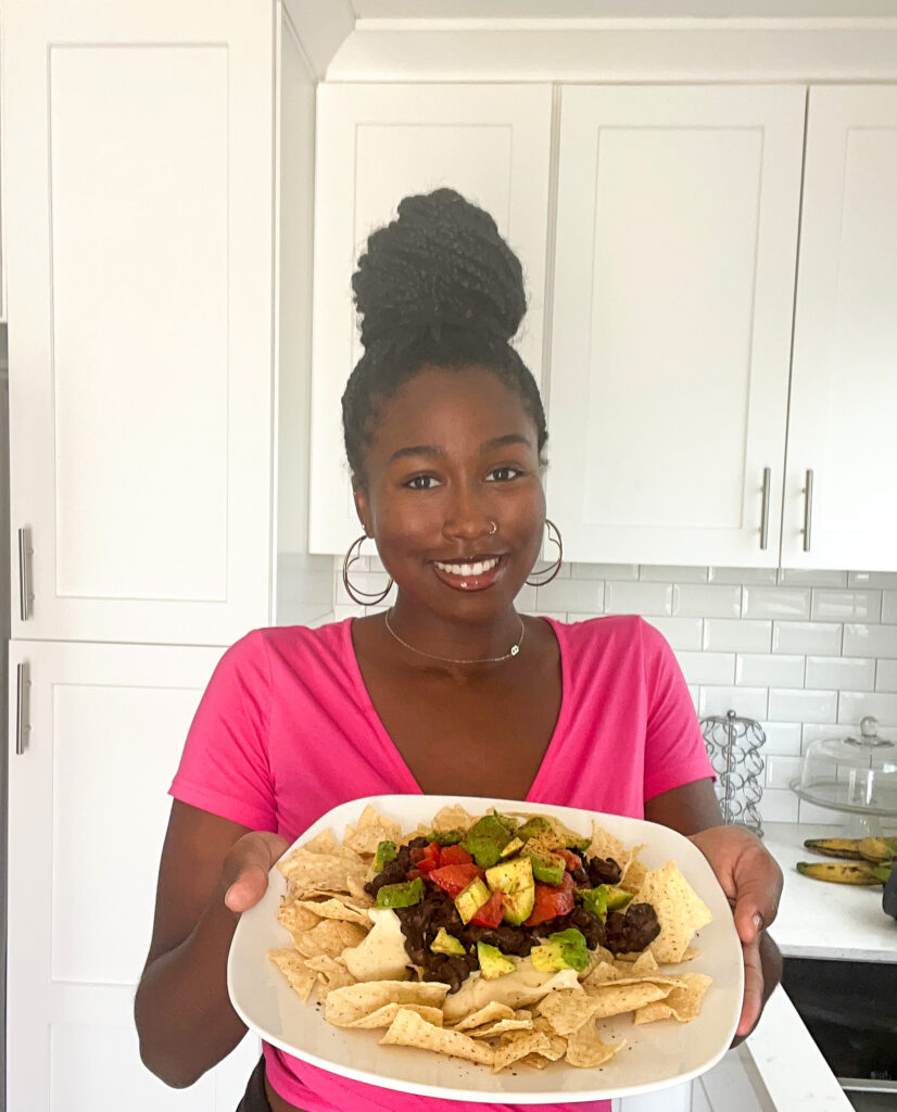 brooklyninthehaus holding dairy free vegan nachos on white plate